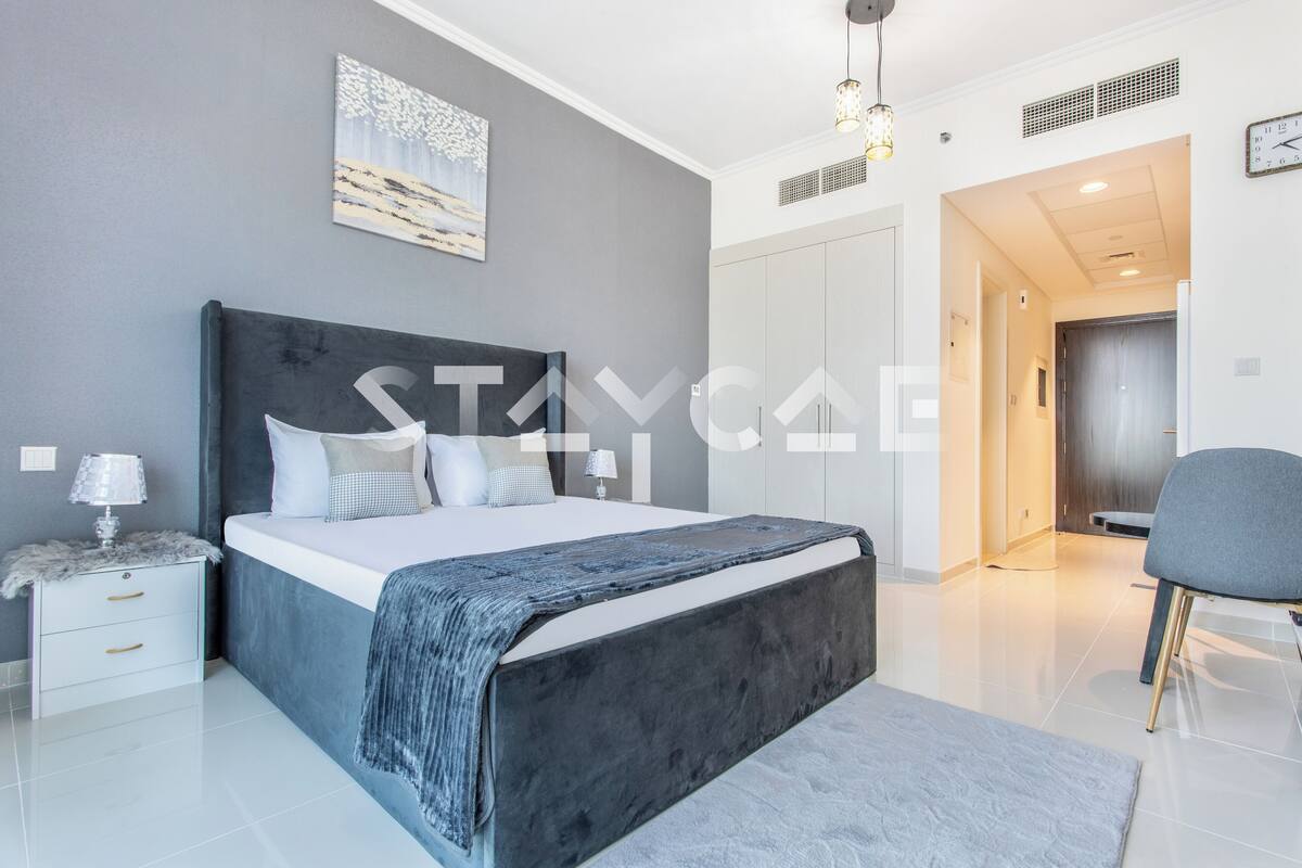 A modern bedroom with a large bed, bedside tables, a wardrobe, and a chair.
