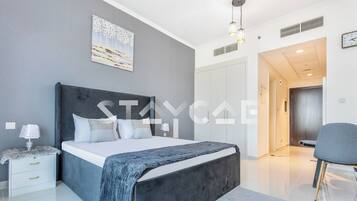 A modern bedroom with a large bed, bedside tables, a wardrobe, and a chair.