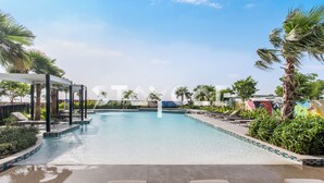 A swimming pool with lounge chairs and palm trees. - Staycae Holiday Homes - Carson Tower (Dubai)