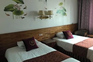 A hotel room with two beds, a wooden headboard, wall-mounted lamps, and a decorative mural. - Jinyuan Hostel (Yueqing)