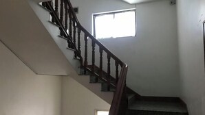 A staircase with wooden balusters and a handrail, leading to a landing with a small window. - Jinyuan Hostel (Yueqing)