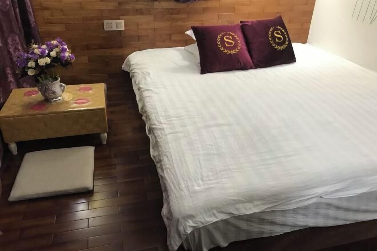 A neatly made bed with white linens and two pillows with a monogram.