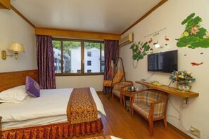 A hotel room with a bed, a desk, a chair, a TV, and a window with curtains. - Jinyuan Hostel (Yueqing)