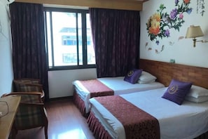 Habitación de hotel con dos camas, un escritorio y una ventana con cortinas.