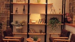 A cozy seating area with two chairs and a small table, surrounded by wooden shelves with various decorative items and books. - Qingfei Hostel (Yueqing)