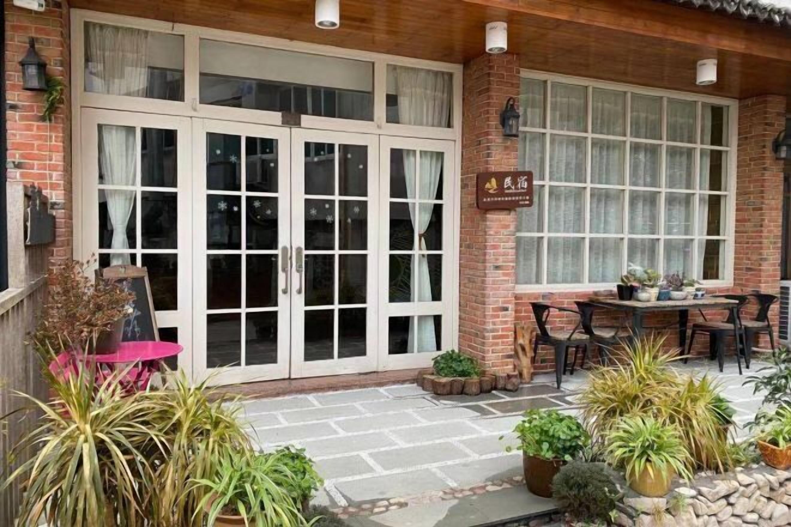 A traditional-style building with a brick facade, large glass doors, and a patio area with outdoor seating.