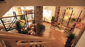 A spacious interior with a staircase, multiple seating areas, and various plants. - Qingfei Hostel (Yueqing)