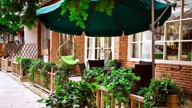 A patio area with hanging chairs, wooden railings, and potted plants. - Qingfei Hostel (Yueqing)
