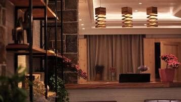 A reception area with a stone wall, wooden reception desk, and a seating area with leather chairs.
