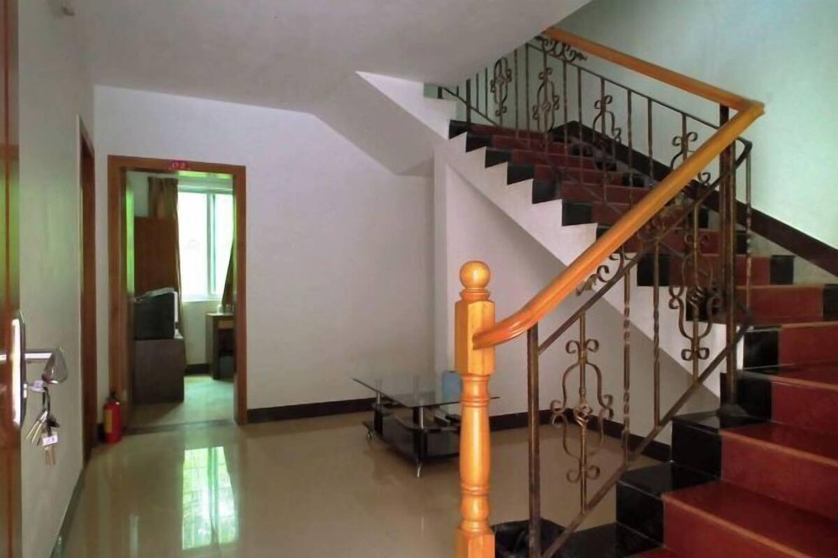 Una escalera con barandilla de madera y balaustradas de metal, que conduce a una plataforma.