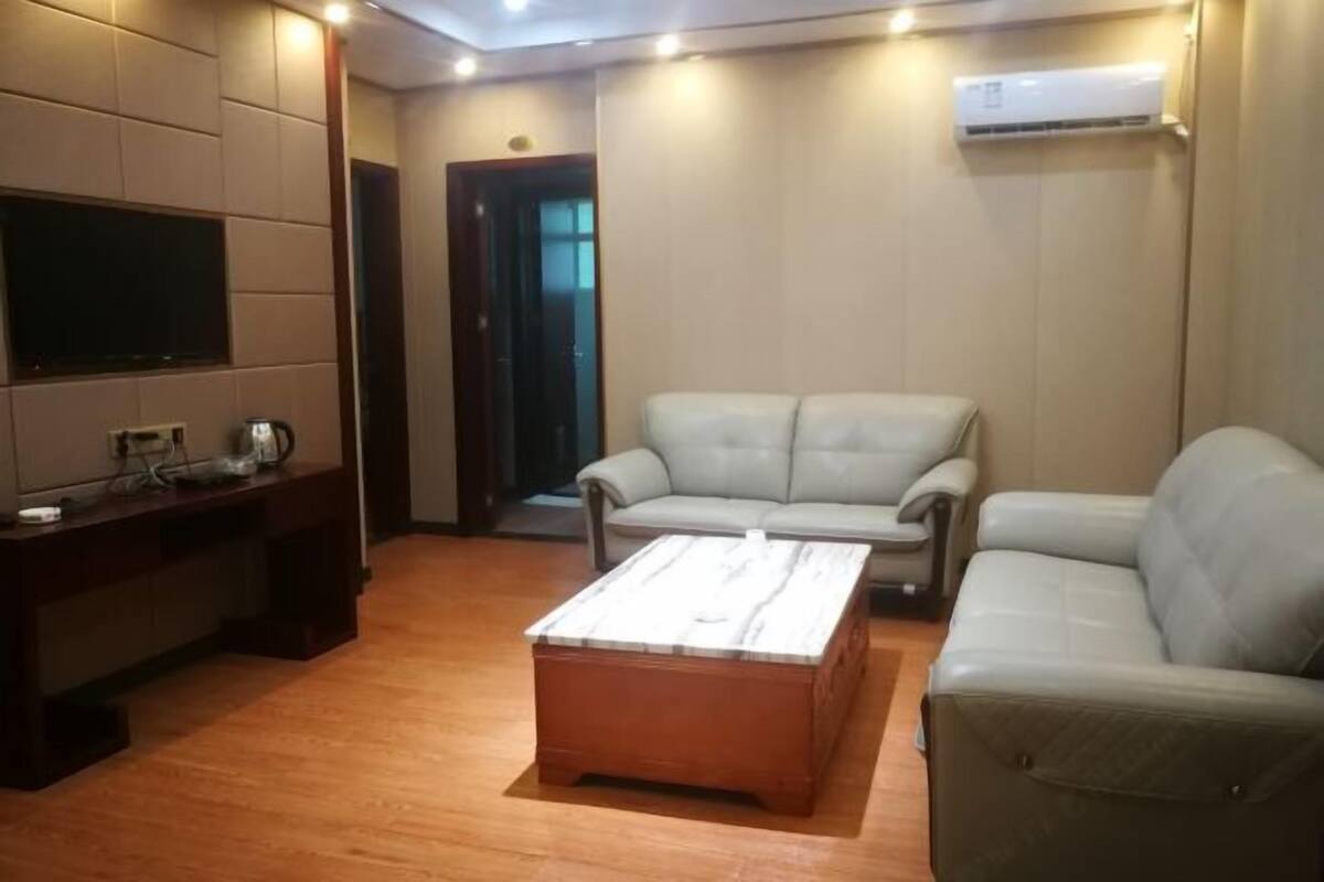Una sala moderna con una mesa de centro de madera, dos sofás grises, un televisor de pantalla plana y un mueble empotrado para entretenimiento.
