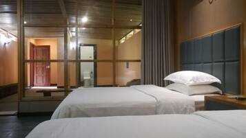 A hotel room with two beds, a wooden headboard, a bedside table, and a mirror.
