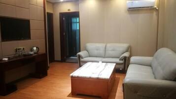 A living room with a sofa, a coffee table, a TV, and an air conditioning unit.
