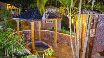 Un belvédère doté d’un jacuzzi, entouré de murs en briques et de palmiers.