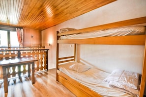 Quarto com beliches, piso e teto de madeira.