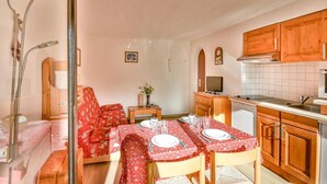 A cozy dining area with a table set for four, wooden cabinets, a television, and a small side table with a vase. - Ski-in/ski-out & foot of the slopes, Ground floor, swimming pool, terrace, parking, 27m², Les Gets (Les Gets)