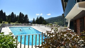 A rectangular swimming pool with a white deck and metal railing, surrounded by a white fence. - Ski-in/ski-out & foot of the slopes, Ground floor, swimming pool, terrace, parking, 27m², Les Gets (Les Gets)