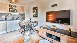 Une cuisine moderne avec un coin repas, un téléviseur à écran plat et des meubles de rangement en bois.
