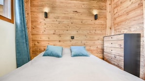 Une pièce avec un mur recouvert de lambris en bois, un lit avec deux oreillers et une commode.