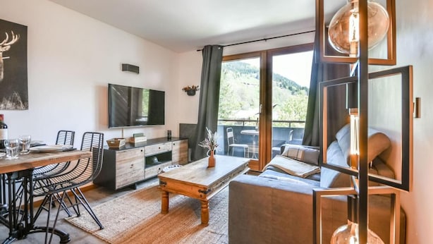 Un salon moderne comprenant un coin repas, un canapé, un téléviseur et une vue sur l’extérieur.