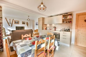 A cozy living room with a sofa, a dining table set for four, and a kitchen area with modern appliances. - Wifi, 1st floor, balcony, ski locker, 48m², Les Gets (Les Gets)