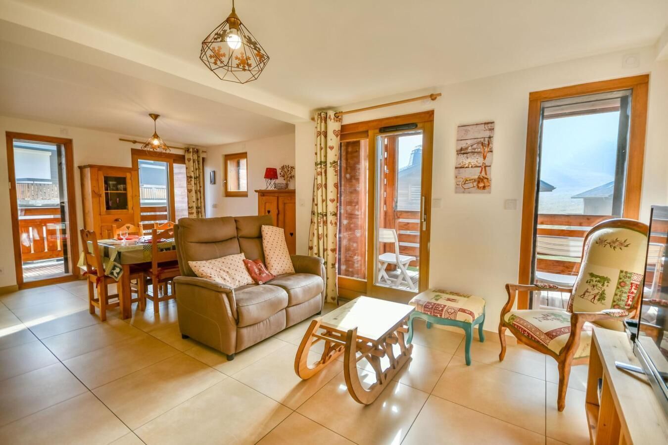 Un salon spacieux comprenant un canapé, une table à manger et un fauteuil à bascule en bois. Une grande fenêtre, agrémentée de rideaux, offre une vue sur l’extérieur.