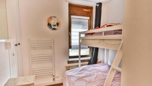 Habitación con literas, un radiador, una mesita y una ventana con cortinas.