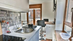 Cocina compacta con lavavajillas integrado, un lavamanos y encimera de madera.