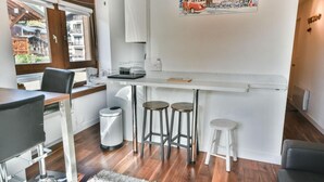 Cocina compacta con barra, mesa de comedor y un pequeño bote de basura.