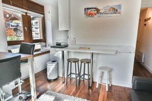 A compact kitchen with a bar area, a dining table, and a small trash bin. - 200m from ski slopes, 1st floor, balcony, tv, ski locker, 28m², Les Gets (Les Gets)