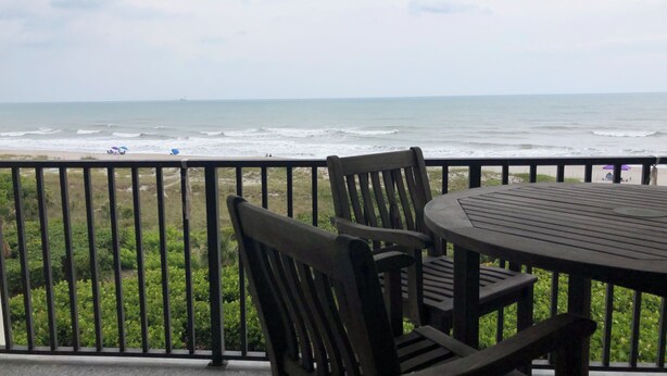A balcony with a view of the ocean, featuring a table and chairs. - Direct Ocean Views, Luxe Living #506 (Cape Canaveral)