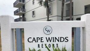 A sign for Cape Winds Resort with a logo and name. - Direct Ocean Views, Luxe Living #506 (Cape Canaveral)