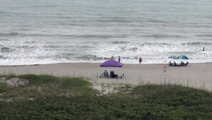 A beach with a purple tent and a blue umbrella. - Direct Ocean Views, Luxe Living #506 (Cape Canaveral)