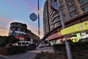A street view with a multi-story building, a curved corner, and a storefront with illuminated signage. - Jinjiang Inn (Yixing Renmin Middle Road Pedestrian Street) (Yixing)