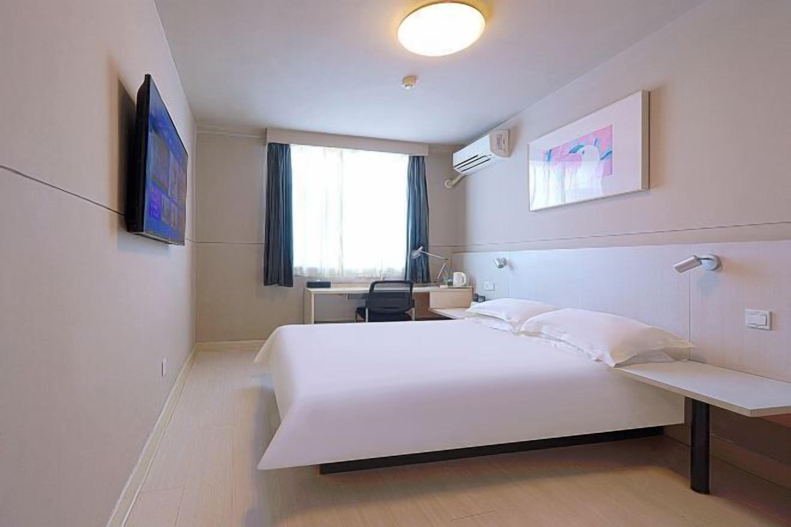 A hotel room with a bed, desk, chair, and artwork on the walls.