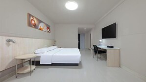 Une chambre d’hôtel équipée d’un lit, d’une table de chevet, d’un bureau, d’une chaise et d’un téléviseur à écran plat fixé au mur.