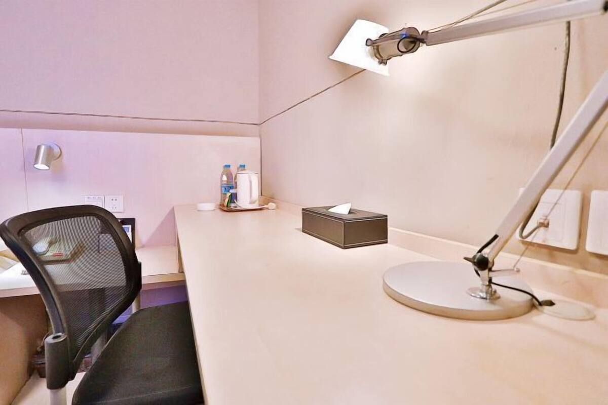A desk with a computer, a chair, a desk lamp, and a tissue box.