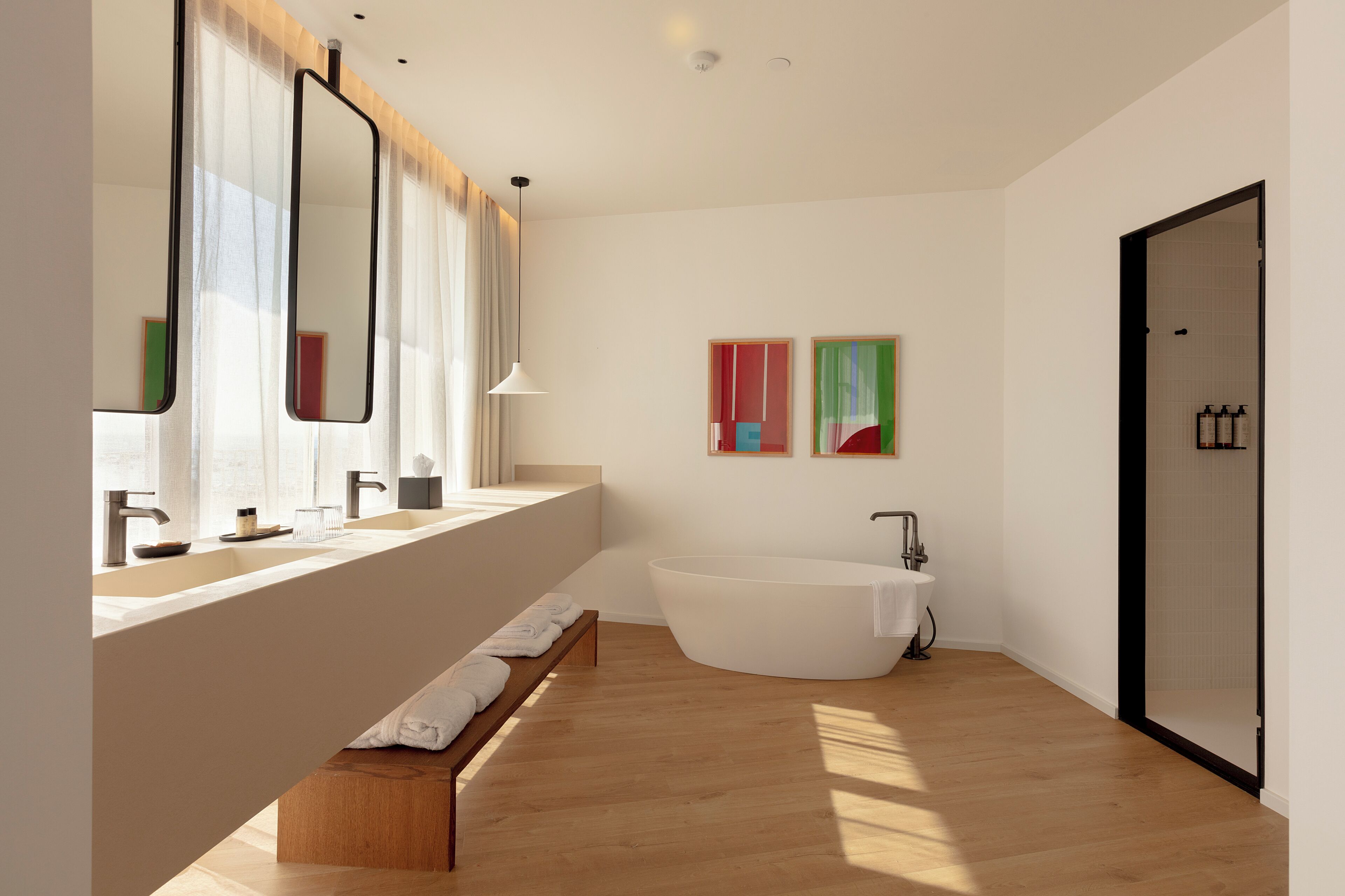 Un baño moderno con una bañera independiente, un banco y un espejo grande.