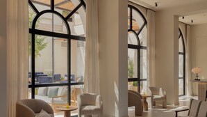 Amplia sala de estar con grandes ventanales, asientos cómodos y vistas al patio exterior.