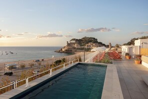 Un espace piscine avec vue sur la mer et accès à la plage.