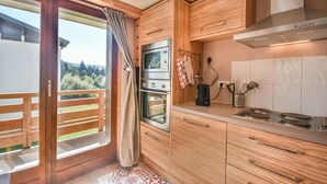 A kitchen with wooden cabinets, a stove, and a window overlooking a balcony.