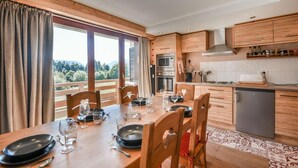 A modern kitchen with wooden cabinets, a dining table set for four, and a view of the outdoors.