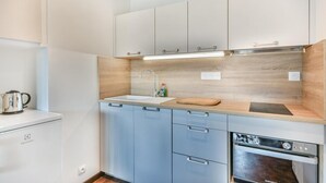 Een moderne keuken met witte kastjes, een houten aanrecht, een roestvrijstalen spoelbak en een inbouwoven.