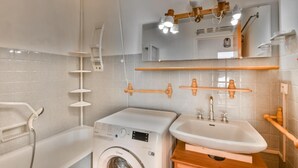 Een moderne badkamer met een wasmachine, een wastafel en een douche.