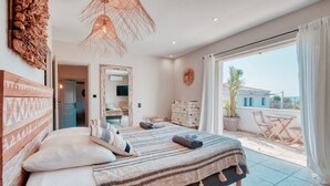 A bedroom with a large bed, a wardrobe, a mirror, and a balcony with a table and chairs.