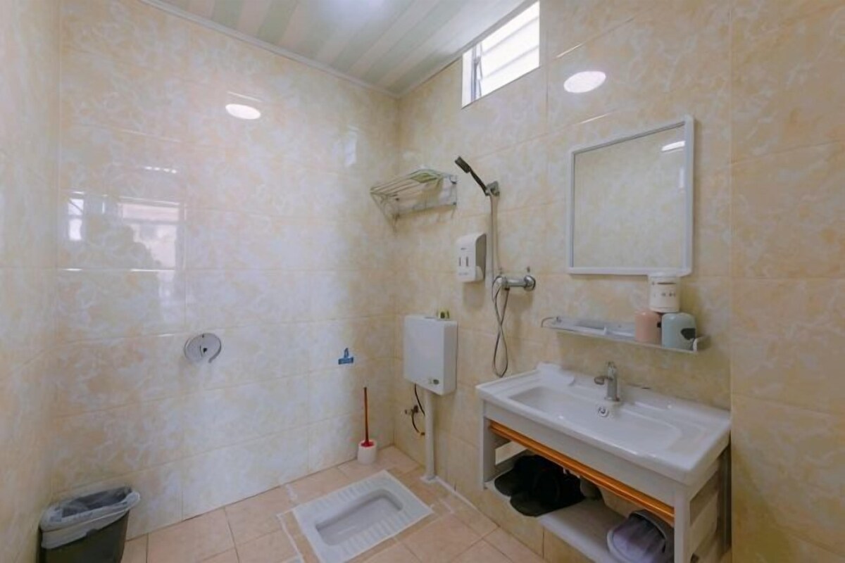 Un baño con ducha, lavamanos, espejo e inodoro.