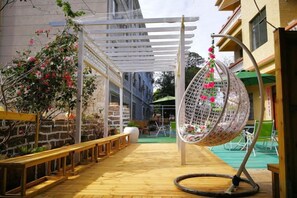 A wooden deck with a hanging chair, a pergola, and a stone wall. - Weizhou Island Shibei Homestay (Shell Beach) (Beihai)
