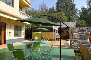 Un patio con mesa y sillas, una zona cubierta y una piscina pequeña.