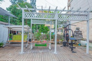 A wooden deck with a white pergola, outdoor exercise equipment, and a hanging swing. - Weizhou Island Shibei Homestay (Shell Beach) (Beihai)