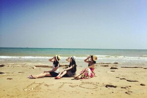 Tres personas sentadas en una playa arenosa con la palabra 'LOVE' escrita en la arena.